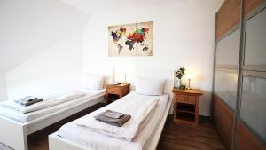 two beds in a room with white walls and wooden floors at Generous & bright flat - private Parking, daylight bathroom - by homekeepers in Zell am Main