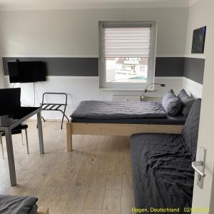 a bedroom with a bed and a desk and a window at Ferienwohnung Hagen in Hagen