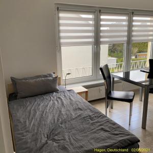 a bedroom with a bed and a desk and a window at Ferienwohnung Hagen in Hagen