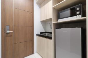 a small kitchen with a microwave and a refrigerator at Mendjangan Residence in Jakarta