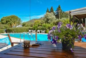 a wooden table with flowers on it next to a pool at Moulinos Studios in Svoronata