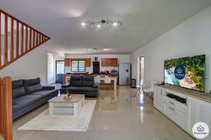 uma sala de estar com um sofá e uma televisão de ecrã plano em Villa Embellia 3 étoiles, 147 m2 pour un séjour nature à Salazie em Salazie