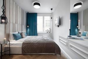 a bedroom with a bed with blue curtains and a window at Elite Apartments Ogarna Prestige in Gdańsk