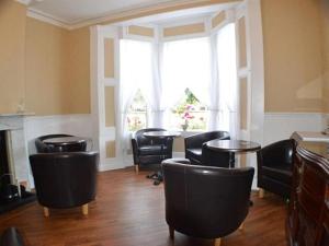 uma sala de espera com cadeiras pretas e uma mesa em The Shrewsbury Guest House em Great Yarmouth