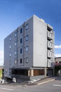 Kita-hamachō的住宿－ALPHABED INN 小樽駅前，街道边的灰色大建筑