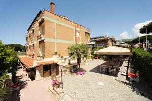 un edificio con un patio con mesas y una sombrilla en Hotel Casa Yvorio, en Terracina