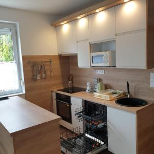 a kitchen with white cabinets and a dishwasher at Mártika Apartment in Siófok