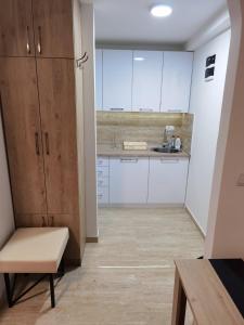 eine Küche mit weißen Schränken und einer Bank in einem Zimmer in der Unterkunft Centar Milena in Aranđelovac