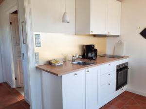 a kitchen with white cabinets and a sink at Feriehus Nord på Rødkærgård in Kerteminde