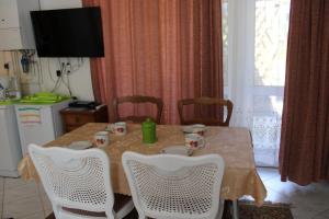 uma mesa de jantar com cadeiras brancas e uma cozinha em Centrum Apartman em Fonyód