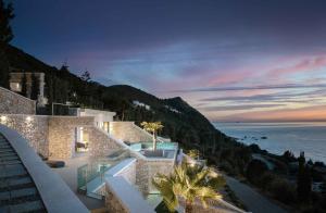 une maison avec vue sur l'océan au crépuscule dans l'établissement THE WAVE TWIN VILLA 1 KATHISMA BEACH Lefkada, à Leucade