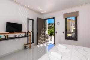 a white room with a bed and a tv and a balcony at Sunny Garden Hotel in Tsilivi