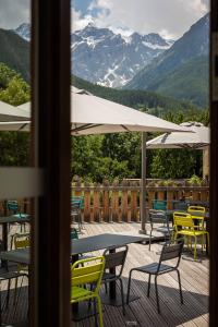 a deck with tables and chairs with mountains in the background at Hôtel Restaurant Le Monêtier in Le Monêtier-les-Bains