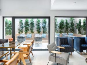 a dining room with tables and chairs and windows at DAYS City Suites in Patra