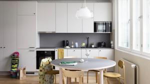 a kitchen with white cabinets and a table and chairs at Bob W Helsinki City Centre in Helsinki