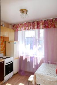 a kitchen with a table and a window with curtains at Уютная квартира на Сибирской 44 in Novosibirsk