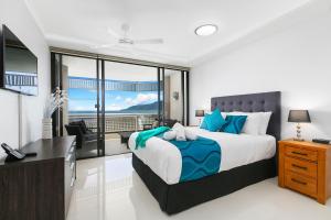 a bedroom with a bed and a desk with a view at Cairns Luxury Seafront Apartment in Cairns