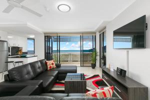a living room with a black leather couch and a kitchen at Cairns Luxury Seafront Apartment in Cairns