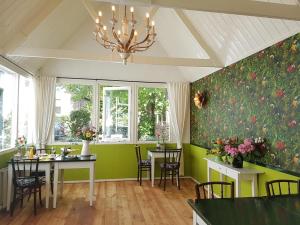 een eetkamer met groene muren en een kroonluchter bij Hotel De Waag in Bergen