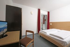 a bedroom with a bed and a desk and a tv at Hotel Villa Verde in Nago-Torbole +50 photos