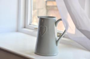 eine Kaffeetasse mit einem Herz auf einem Fensterbrett in der Unterkunft Whiston Hall in Whiston