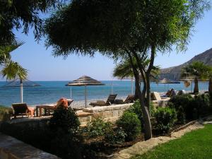 ein Strand mit Stühlen und Sonnenschirmen und das Meer in der Unterkunft Villa Rossa in Pissouri