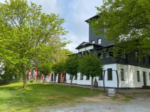 ein Schwarz-Weiß-Gebäude mit Bäumen davor in der Unterkunft Ferienwohnung in der Brennerei Mönchgut in Middelhagen