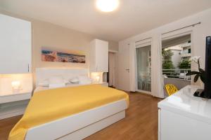 a bedroom with a yellow bed and a balcony at Apartments Milana 2 in Tučepi