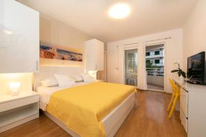 a bedroom with a yellow bed and a window at Apartments Milana 2 in Tučepi
