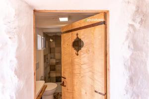 a bathroom with a wooden door with a toilet at I Trulli di Emma by Apulia Home in Alliste +36 photos