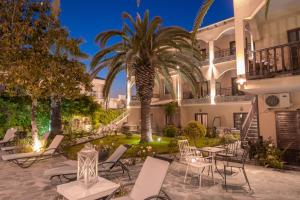 a courtyard with chairs and a palm tree in front of a building at Villa Pipini Luxury Studios in Limenas