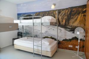 een slaapkamer met 2 stapelbedden en een muurschildering bij HI Arrifana Destination Hostel in Aljezur +37 foto's