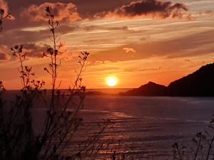 a sunset over a body of water with mountains at Les Sables Blancs de la Liscia in Calcatoggio