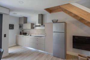 a kitchen with white cabinets and a refrigerator at Adosado Marea Baja 1 zona de playa y montaña in Llanes