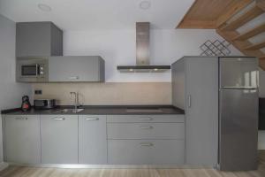 a kitchen with white cabinets and a stainless steel refrigerator at AdosadoDuplex Marea Baja 3 Zona Playa Ideal familias parejas y amigos in Llanes