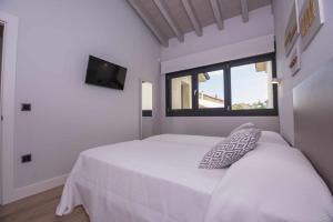 a bedroom with a white bed and a window at Adosado-Duplex Marea Baja 3 zona de playa y montañ in Llanes