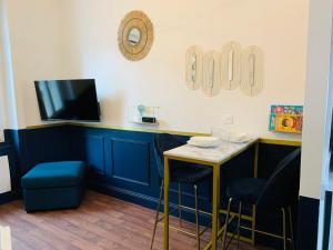 eine Bar mit einem Tisch, 2 Stühlen und einem TV in der Unterkunft Homard & Fox, Le Féart, Studio avec coin terrasse & barbecue in Dinard