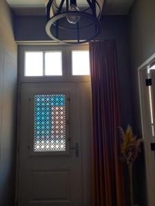 een deur met een raam en een kroonluchter erboven bij Vakantiehuis De Oude Bakkerij in Katwijk aan Zee