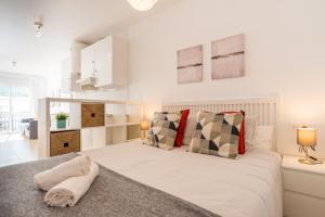 ein weißes Schlafzimmer mit einem großen Bett mit Kissen in der Unterkunft Modern studio apartments Benalmadena in Benalmádena