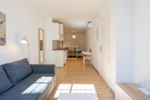 a living room with a blue couch and a kitchen at Modern studio apartments Benalmadena in Benalmádena