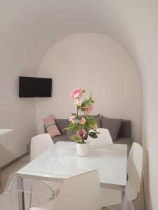 une table à manger blanche avec des chaises blanches et un vase avec des fleurs dans l'établissement Casa Kale', à Polignano a Mare