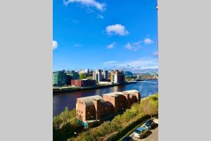 une vue sur une rivière avec une ville en arrière-plan dans l'établissement Stylish Quayside 2 bed apartment with beautiful river views, à Newcastle upon Tyne