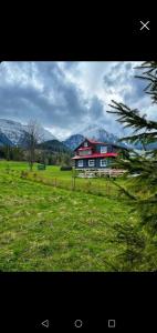 a large red barn in a field with mountains in the background at Chata Liptak in Ždiar