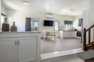 a kitchen and living room with white cabinets and a table at Remezzo Aegean Mare Maisonette in Livadi Astypalaias