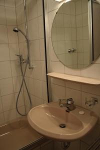 
a white sink sitting under a mirror in a bathroom at Hotel Garni Geisler in Cologne
