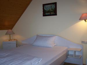 um quarto com uma cama branca e uma mesa de cabeceira com um candeeiro em Gasthof Engel Steinbach em Külsheim