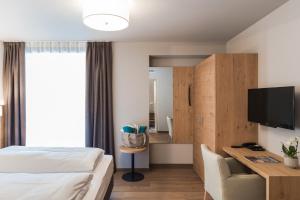 Habitación de hotel con cama, escritorio y TV. en Lifestyle Hotel Alpin en Schenna