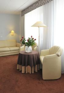 ein Wohnzimmer mit einer Couch und einem Tisch mit Blumen darauf in der Unterkunft Hotel Sport in Bełchatów