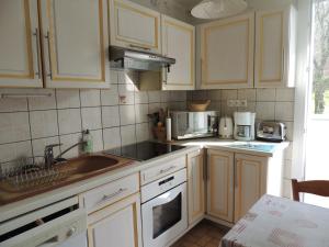 a kitchen with white cabinets and a sink at Appartement 2 pièces près des thermes in Bagnoles de l'Orne