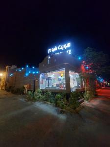 een restaurant met 's nachts een neonbord bij شاليهات سويت هوم الدرب الكدره in Ad Darb